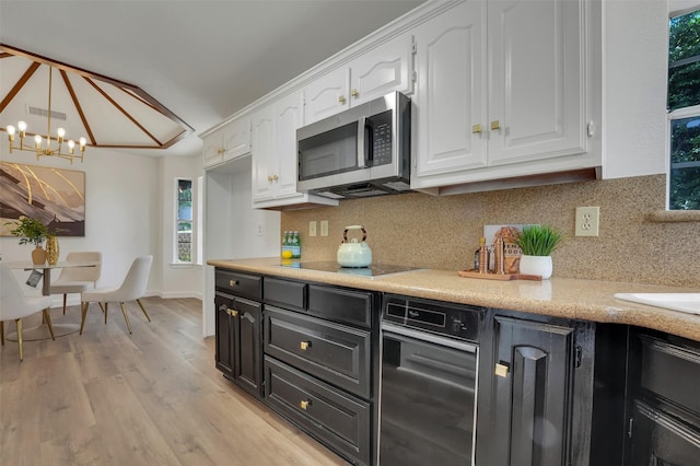 4909 Berkeley Ct, Garland, TX 75043 - kitchen featuring stainless steel microwave, white cabinetry, black electric stovetop, decorative backsplash, and a chandelier