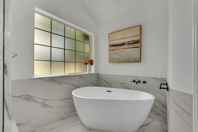 4909 Berkeley Ct, Garland, TX 75043 - bathroom with marble tiled flooring, tile walls, a freestanding tub, and a wainscoted wall