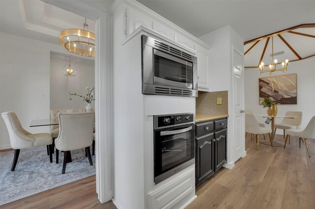4909 Berkeley Ct, Garland, TX 75043 - kitchen with stainless steel appliances, a chandelier, light wood-style flooring, white cabinetry, and light countertops