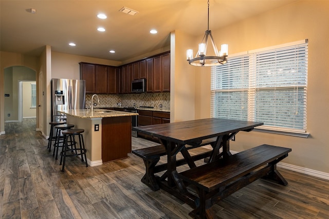 4825 Lazy Oaks St, Fort Worth, TX 76244 - kitchen with stainless steel appliances, arched walkways, a kitchen island with sink, a chandelier, and dark brown cabinets
