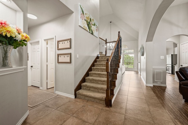 11404 Grapeleaf Dr, Fort Worth, TX 76244 - stairs with arched walkways, high vaulted ceiling, tile patterned flooring, and baseboards