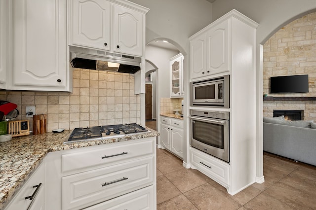11404 Grapeleaf Dr, Fort Worth, TX 76244 - kitchen featuring stainless steel appliances, under cabinet range hood, arched walkways, and light stone countertops