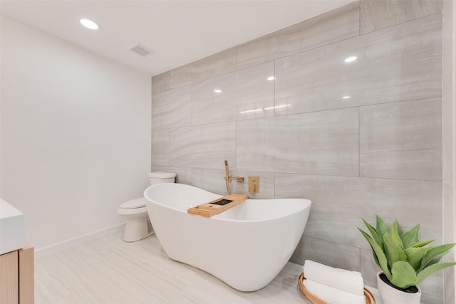 1720 Meadow Valley Ln, Dallas, TX 75232 - full bath featuring a freestanding bath, toilet, vanity, tile walls, and baseboards