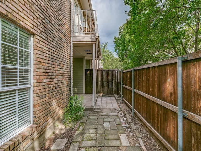 7151 Gaston Ave Unit 906, Dallas, TX 75214 - view of home's exterior featuring a balcony, brick siding, a fenced backyard, and a patio area