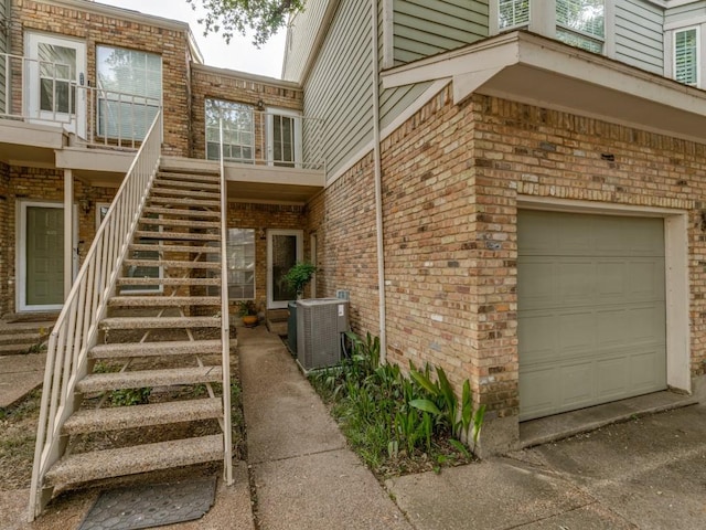 7151 Gaston Ave Unit 906, Dallas, TX 75214 - doorway to property featuring a garage, cooling unit, brick siding, and concrete driveway