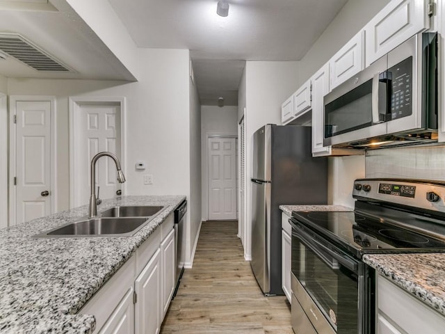7151 Gaston Ave Unit 906, Dallas, TX 75214 - kitchen featuring stainless steel appliances, a sink, light wood finished floors, and white cabinetry