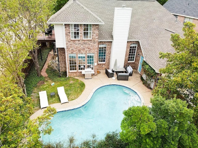 1529 Arrowhead Ln, Carrollton, TX 75007 - rear view of house with brick siding, a patio area, an outdoor pool, a shingled roof, and an outdoor living space