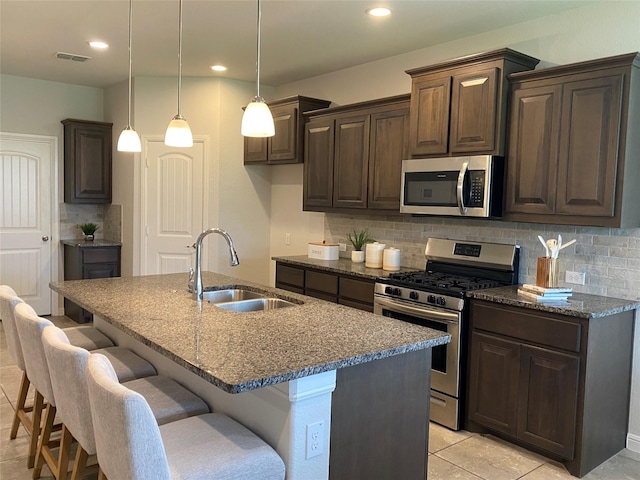 1037 Madelia Ave, Fort Worth, TX 76177 - kitchen featuring stainless steel appliances, a sink, backsplash, dark stone countertops, and dark brown cabinetry