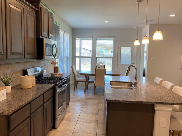 1037 Madelia Ave, Fort Worth, TX 76177 - kitchen featuring appliances with stainless steel finishes, a sink, decorative backsplash, a breakfast bar area, and light tile patterned floors