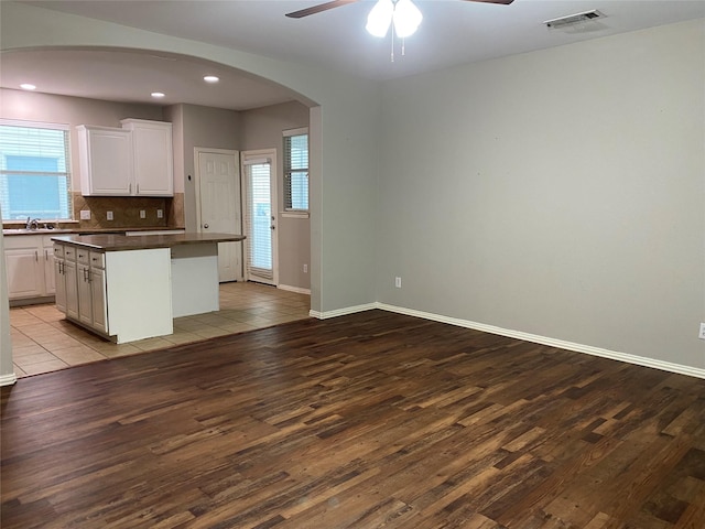 1705 Spanish Moss Way, Savannah, TX 76227 - kitchen featuring dark countertops, wood finished floors, a center island, a ceiling fan, and arched walkways