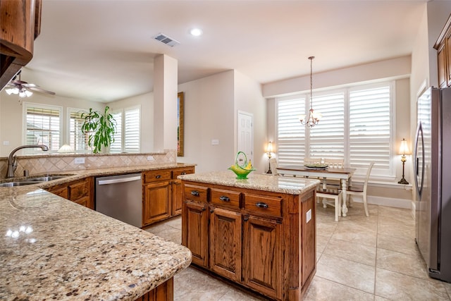 2636 Deer Hollow Dr, Little Elm, TX 75068 - kitchen with a sink, appliances with stainless steel finishes, brown cabinetry, decorative backsplash, and a chandelier