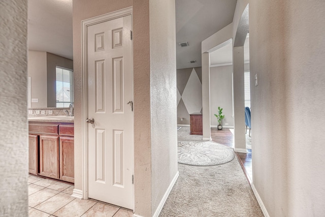 6939 Truth Dr, Dallas, TX 75236 - hallway featuring a textured wall, a sink, baseboards, and light tile patterned flooring