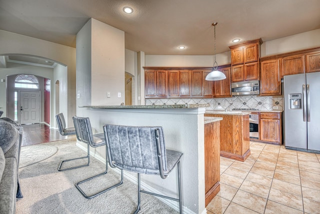 6939 Truth Dr, Dallas, TX 75236 - kitchen with stainless steel appliances, arched walkways, brown cabinetry, decorative backsplash, and recessed lighting