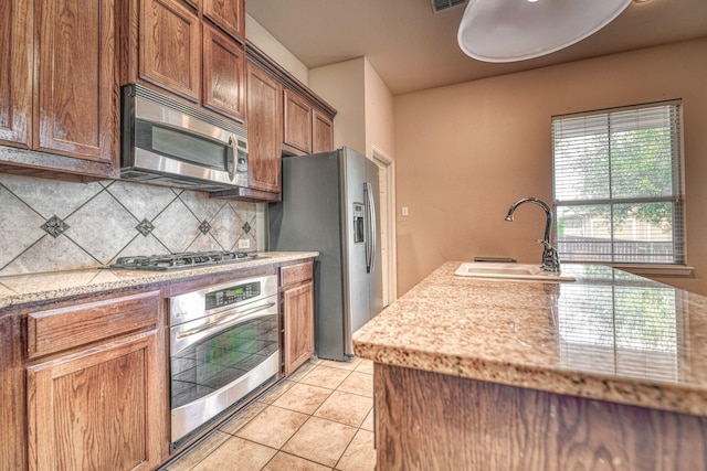 6939 Truth Dr, Dallas, TX 75236 - kitchen with appliances with stainless steel finishes, a sink, tasteful backsplash, light tile patterned floors, and brown cabinetry