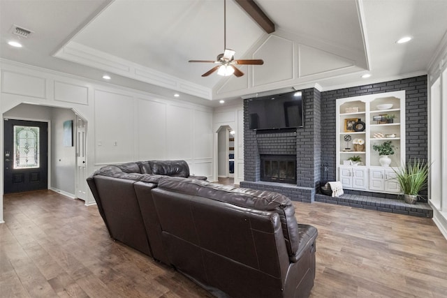 517 Sunset Dr, Hurst, TX 76054 - living room featuring a ceiling fan, a decorative wall, a fireplace, wood finished floors, and built in features