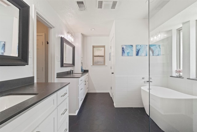517 Sunset Dr, Hurst, TX 76054 - bathroom featuring two vanities, tile patterned flooring, a soaking tub, tile walls, and baseboards