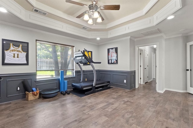 517 Sunset Dr, Hurst, TX 76054 - exercise area featuring ceiling fan, wood finished floors, ornamental molding, a tray ceiling, and a wainscoted wall