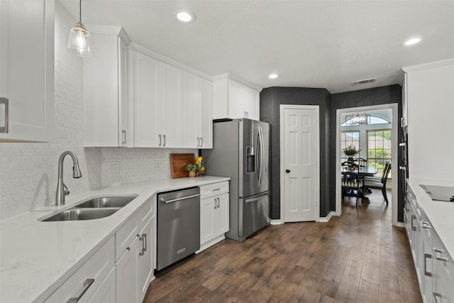517 Sunset Dr, Hurst, TX 76054 - kitchen featuring stainless steel appliances, a sink, dark wood finished floors, decorative backsplash, and white cabinets