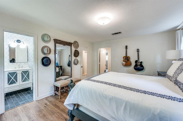 1913 Windlea Dr, Euless, TX 76040 - bedroom with wood finished floors, a textured ceiling, and ensuite bathroom
