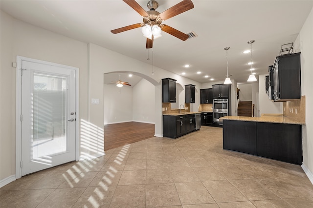 5505 Wisdom Ct, Waco, TX 76708 - kitchen featuring dark cabinets, a ceiling fan, stainless steel double oven, a sink, and arched walkways