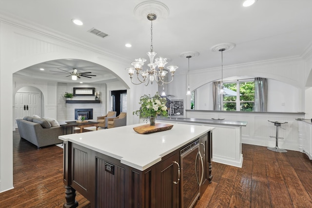1208 Chandler Cir, Prosper, TX 75078 - kitchen with wine cooler, a center island, a fireplace, a ceiling fan, and arched walkways