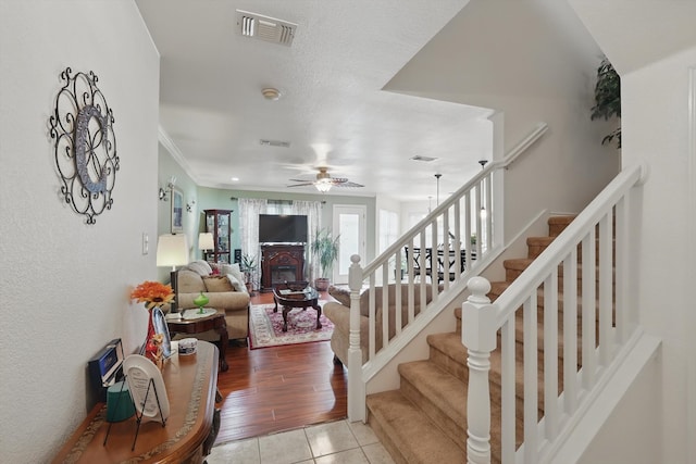 9829 Stoney Bridge Rd, Fort Worth, TX 76108 - tiled living area with a ceiling fan, stairs, a glass covered fireplace, and crown molding