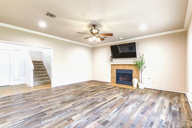 1104 Bayshore St, Allen, TX 75002 - unfurnished living room with a ceiling fan, a tiled fireplace, wood finished floors, stairs, and crown molding