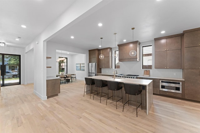 4516 Shenandoah Ave, University Park, TX 75205 - kitchen with stainless steel appliances, a kitchen breakfast bar, a sink, light wood finished floors, and recessed lighting