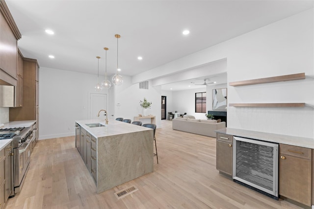 4516 Shenandoah Ave, University Park, TX 75205 - kitchen with wine cooler, range with two ovens, a sink, light wood-type flooring, and an island with sink