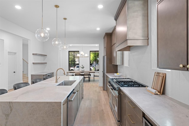 4516 Shenandoah Ave, University Park, TX 75205 - kitchen featuring appliances with stainless steel finishes, a sink, custom exhaust hood, a center island with sink, and light wood-style floors