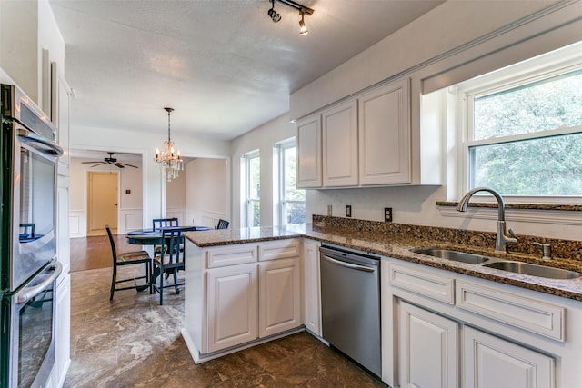 2831 Creekwood Ct, Grapevine, TX 76051 - kitchen with appliances with stainless steel finishes, a sink, a peninsula, a chandelier, and dark stone countertops