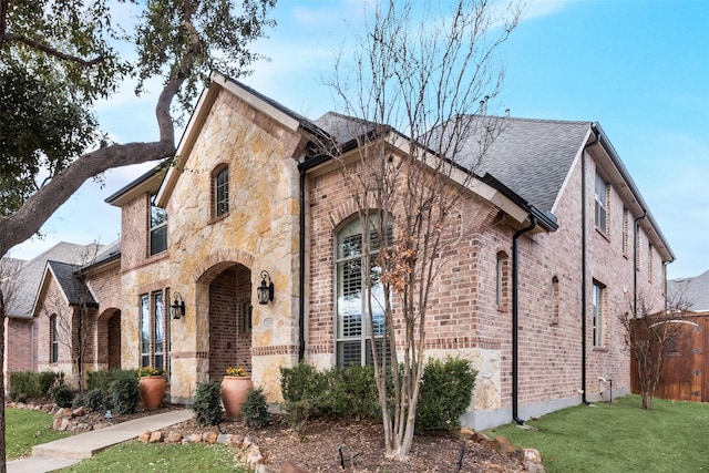 1542 Sandia Ln, Frisco, TX 75033 - tudor-style house featuring stone siding, brick siding, a front lawn, and a shingled roof