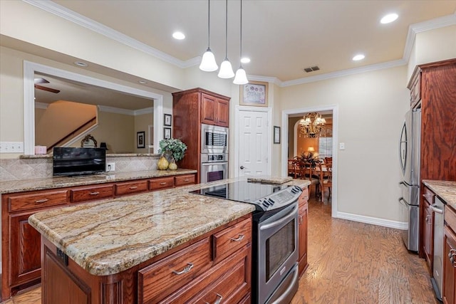 6717 Savannah Ln, Fort Worth, TX 76132 - kitchen with appliances with stainless steel finishes, a center island, light wood finished floors, a chandelier, and ornamental molding