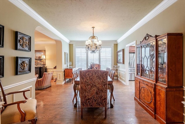 6717 Savannah Ln, Fort Worth, TX 76132 - dining area featuring a chandelier, crown molding, a textured ceiling, a decorative wall, and arched walkways