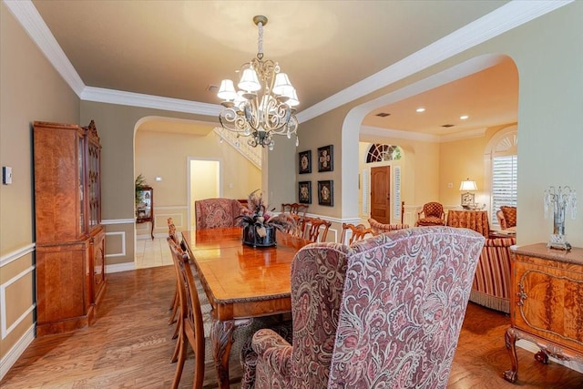 6717 Savannah Ln, Fort Worth, TX 76132 - dining area featuring arched walkways, a chandelier, crown molding, wood finished floors, and a wainscoted wall