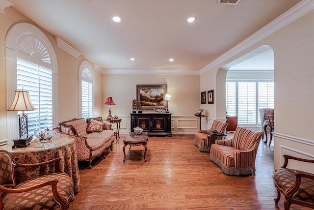 6717 Savannah Ln, Fort Worth, TX 76132 - living room featuring ornamental molding, a decorative wall, healthy amount of natural light, arched walkways, and wood finished floors