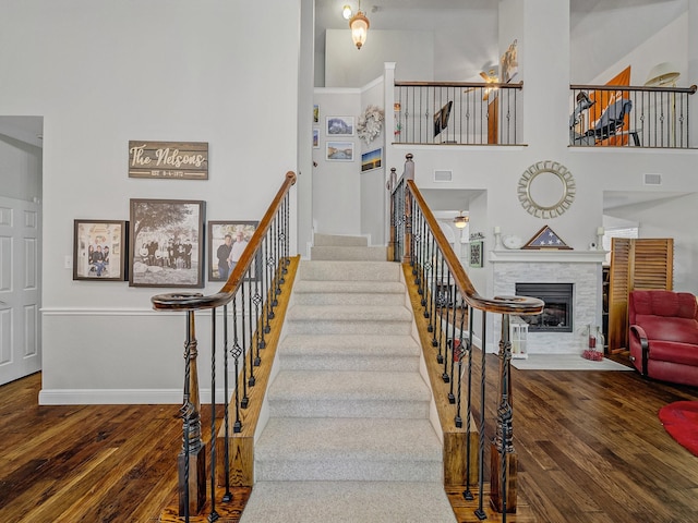 525 Sir Roland Dr, Grand Prairie, TX 75052 - staircase with wood-type flooring, a fireplace with flush hearth, baseboards, and a high ceiling