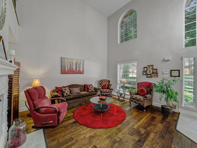 525 Sir Roland Dr, Grand Prairie, TX 75052 - living area with hardwood / wood-style floors, a towering ceiling, a fireplace, baseboards, and healthy amount of natural light