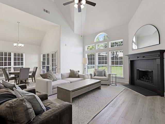 2231 Cold Water Dr, Prosper, TX 75078 - living room featuring a fireplace, high vaulted ceiling, light wood-style floors, a chandelier, and a ceiling fan