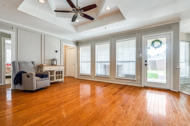 2332 Heatherwoods Way, Carrollton, TX 75007 - living room with a decorative wall, a raised ceiling, light wood finished floors, ceiling fan, and ornamental molding