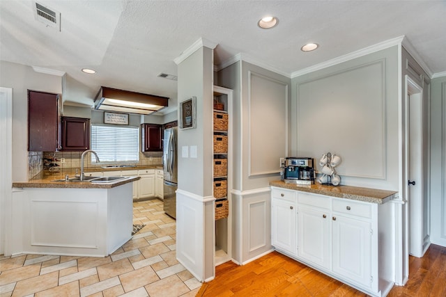 2332 Heatherwoods Way, Carrollton, TX 75007 - kitchen featuring a sink, freestanding refrigerator, tasteful backsplash, crown molding, and a decorative wall