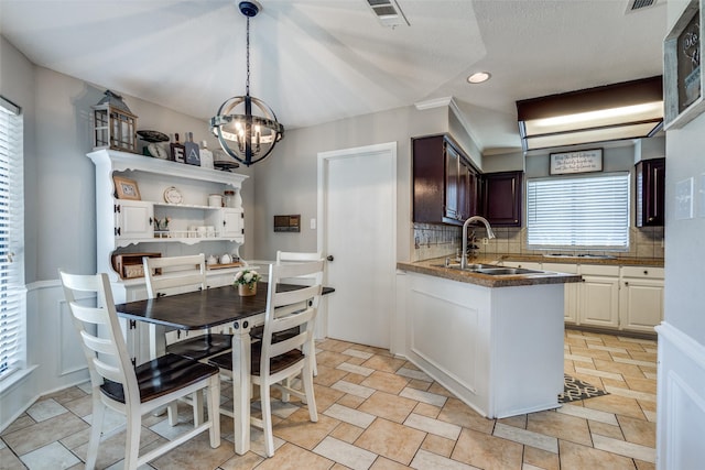 2332 Heatherwoods Way, Carrollton, TX 75007 - kitchen with a sink, a chandelier, decorative backsplash, dark countertops, and a peninsula
