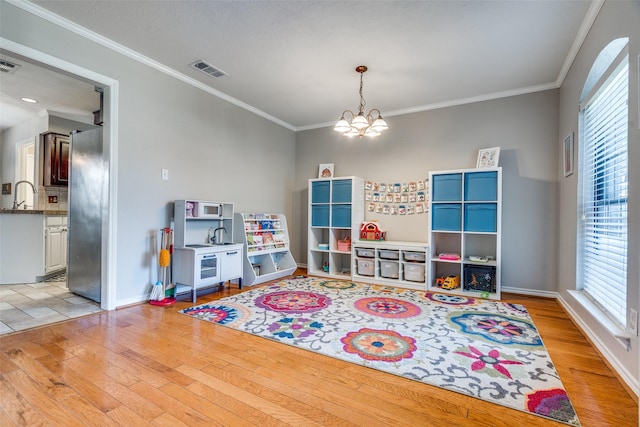 2332 Heatherwoods Way, Carrollton, TX 75007 - rec room featuring light wood-style flooring, a chandelier, crown molding, baseboards, and a sink