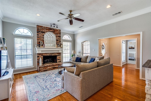 2332 Heatherwoods Way, Carrollton, TX 75007 - living area with ceiling fan, a textured ceiling, a brick fireplace, plenty of natural light, and crown molding
