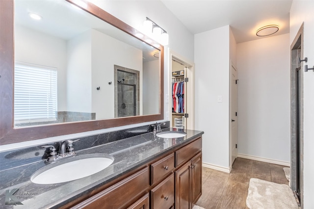 4709 Spring Creek Rd, Abilene, TX 79602 - full bathroom featuring a shower stall, double vanity, wood finished floors, a walk in closet, and baseboards