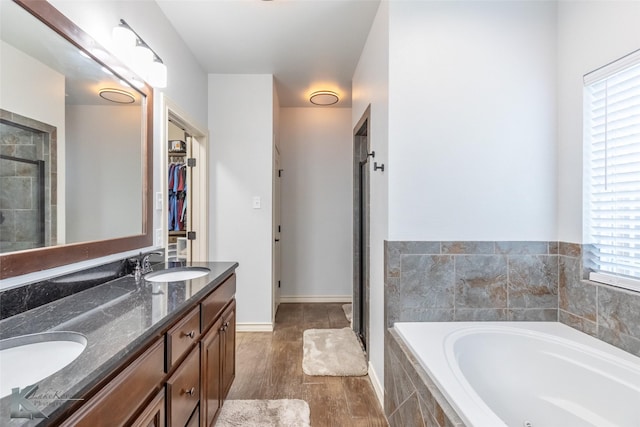 4709 Spring Creek Rd, Abilene, TX 79602 - bathroom featuring double vanity, a bath, wood finished floors, a shower stall, and a walk in closet