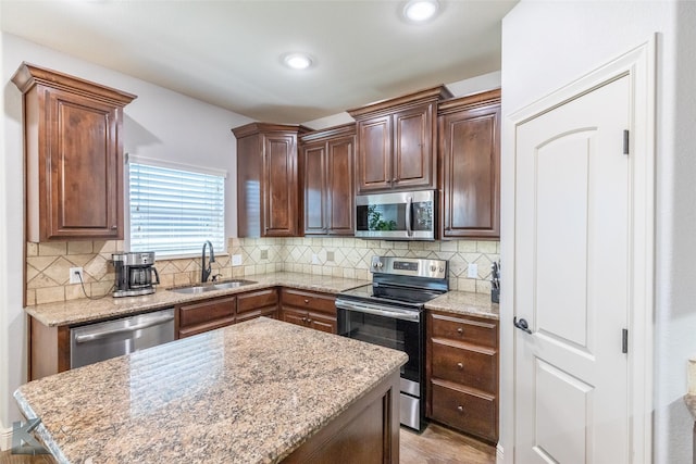4709 Spring Creek Rd, Abilene, TX 79602 - kitchen with stainless steel appliances, a sink, backsplash, a center island, and light wood-style flooring