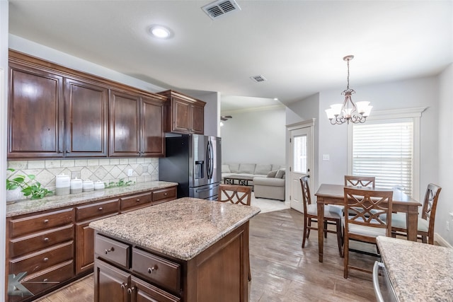 4709 Spring Creek Rd, Abilene, TX 79602 - kitchen featuring stainless steel refrigerator with ice dispenser, a chandelier, open floor plan, light wood-style floors, and tasteful backsplash