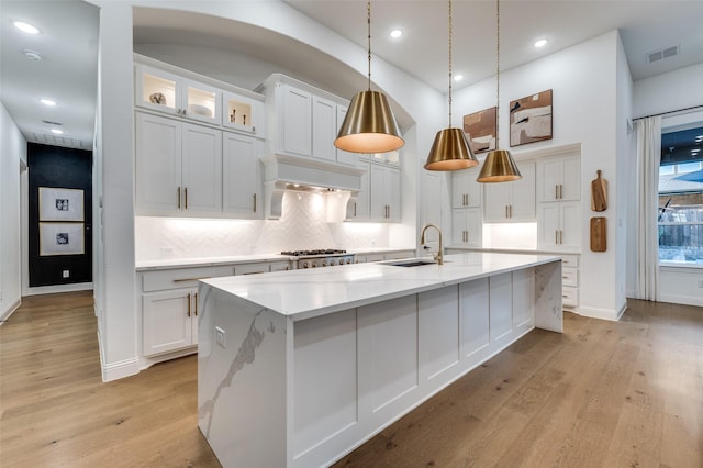 3201 Sunday Silence Ln, Celina, TX 75009 - kitchen with a sink, decorative backsplash, white cabinets, a spacious island, and light wood finished floors