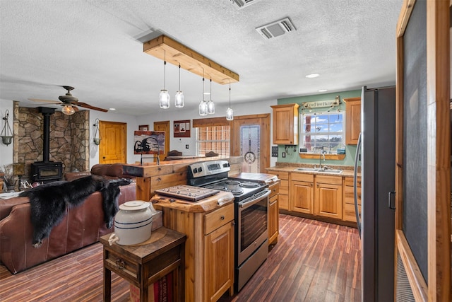 227 W Lipan Dr, Lipan, TX 76462 - kitchen with stainless steel appliances, open floor plan, a sink, a wood stove, and a textured ceiling